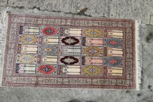 A Turkish silk prayer rug with twenty-five panels and Koranic verse border, 50" x 27 1/2" approx