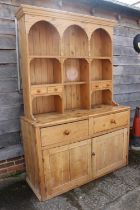 A waxed pine dresser, the upper section with arcade and four spice drawers over two drawers and