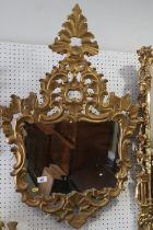 An 18th century Venetian carved giltwood wall mirror with shaped plate and scroll crest, 36" x 24"