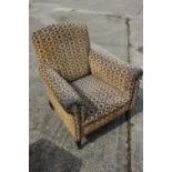 An Edwardian low seat armchair, upholstered in a geometric fabric, on square taper supports