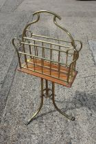 A brass and oak revolving magazine rack, on tripod splayed supports with paw feet, 29 1/2" high