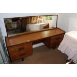 A 1960s teak knee hole dressing table, fitted four drawers and mirror over, 66" wide x 18" deep x