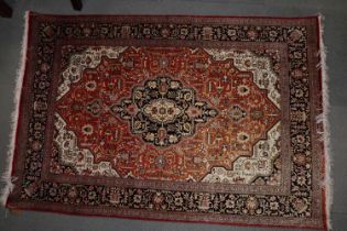 A Qum silk pile rug with geometric central medallion on a rust ground and multi-border in shades