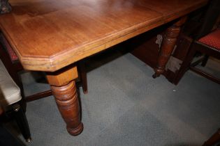 A late Victorian walnut extending dining table with cut corners and extra leaf, on turned