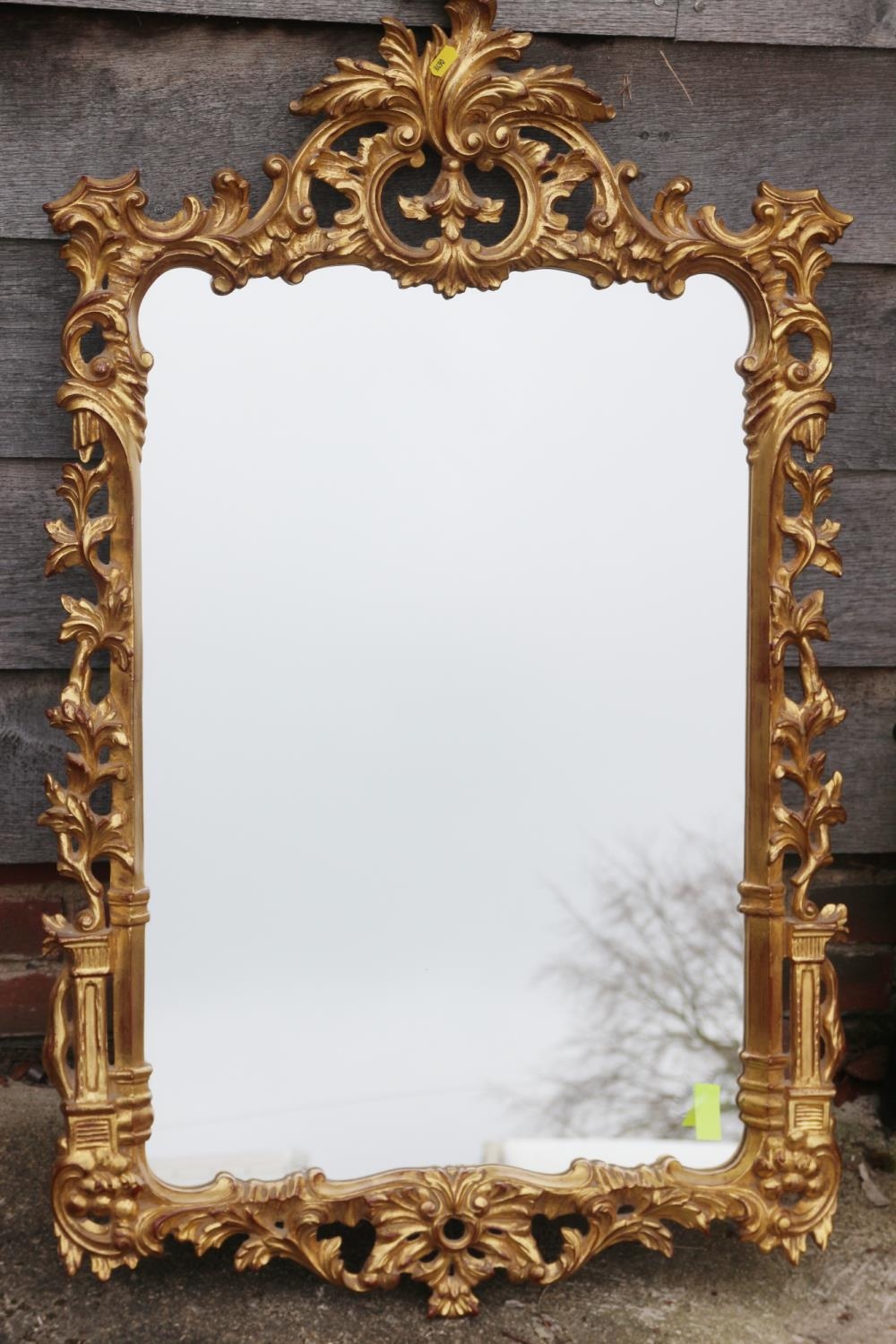 A carved giltwood framed wall mirror of Chippendale design with scroll crest, 42" x 25" overall