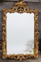 A carved giltwood framed wall mirror of Chippendale design with scroll crest, 42" x 25" overall