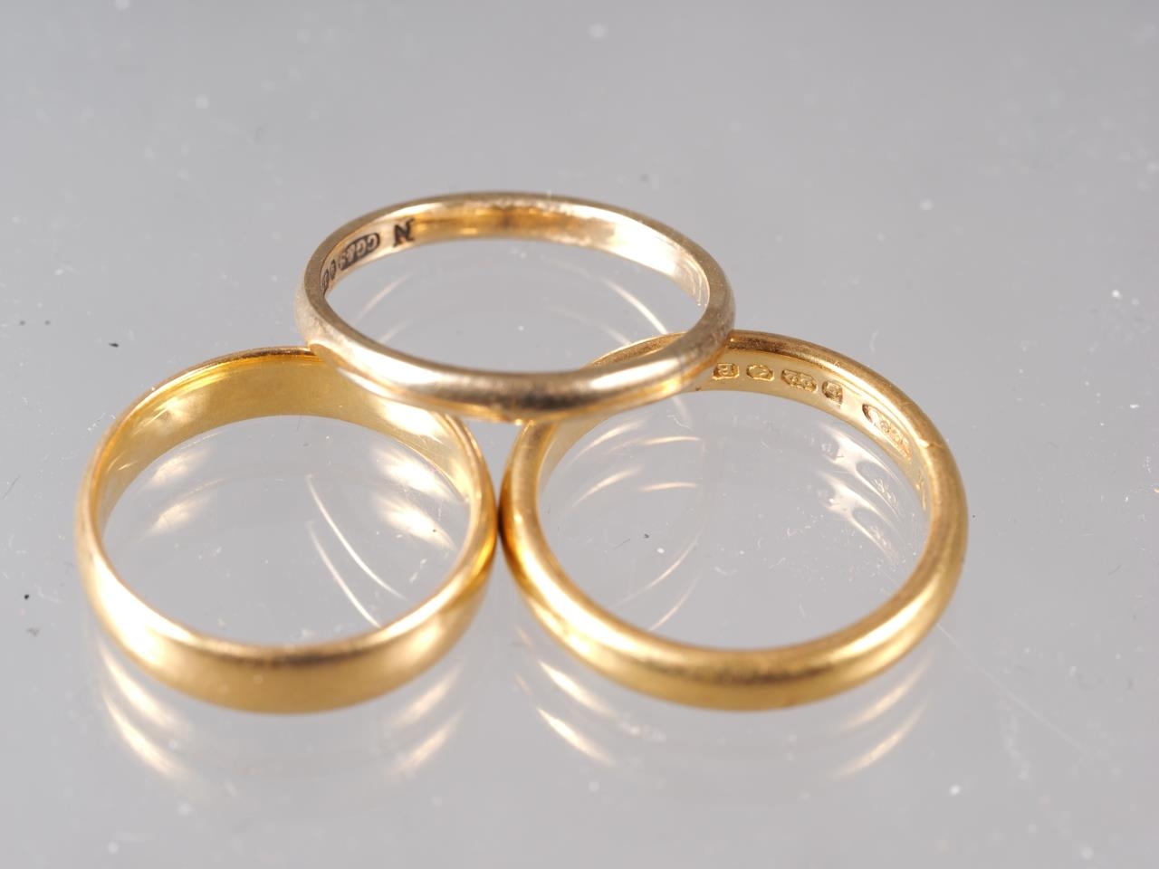 A 22ct gold wedding band, size N, 5.5g, another similar, size L, 4.2g, and a 9ct gold wedding