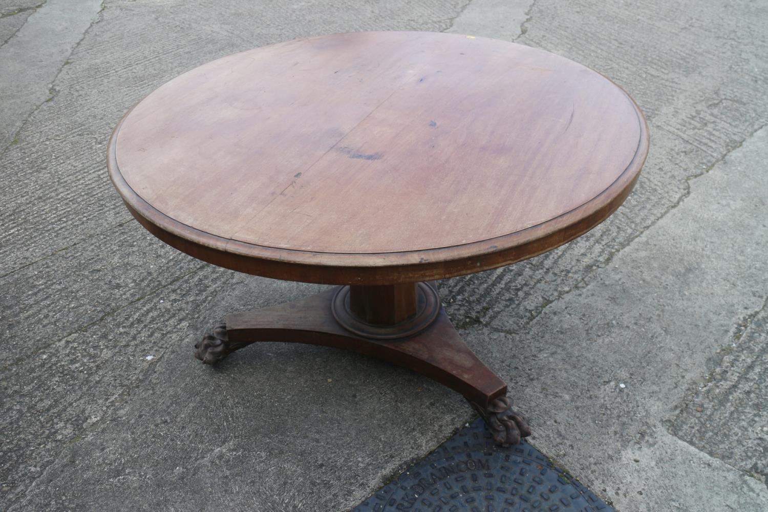 A mid Victorian mahogany circular tilt top dining table, on faceted column, triform base and lion