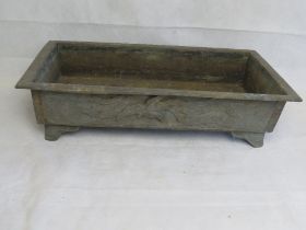 A Chinese rectangular shaped metal planter having three toe dragon and clouds to one side and