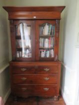 A late Victorian bookcase on chest, pediment top over twin glazed doors having shelves within,