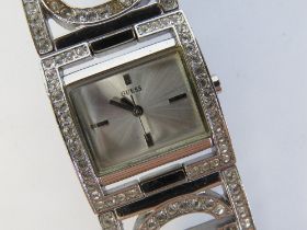 A ladies white stone encrusted wrist watch by Guess, case back deficient.