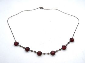 A white metal early 20th century necklace set with red paste stones,