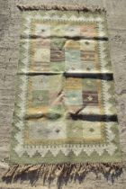 A green ground geometric pattern rug, handwoven 100% wool, measuring approx 90 x 160cm.