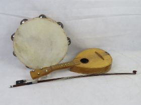 A Ukulele, a tambourine and a violin bow. Three items.