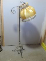 A wrought iron floor standing lamp with silk shade.