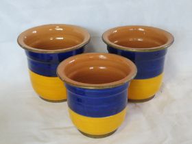 A set of three glazed terracotta plant pots.