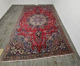 A large red ground Oriental rug, measuring approx 288 x 188cm.