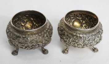 A pair of white metal salts having heavily carved decoration throughout, 104.4g.