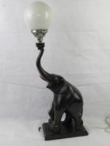 A delightful Art Deco table lamp in the form of an elephant raising a ball upon its trunk,