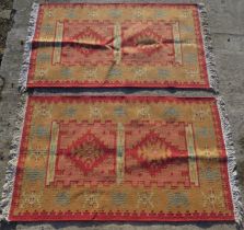A pair of red ground geometric pattern rugs, each measuring approx 90 x 150cm.