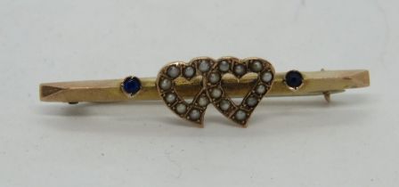 A 9ct gold sweetheart brooch set with seed pearls and sapphires in a double heart design,