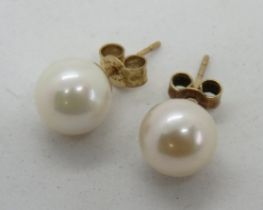 A pair of white pearl earrings, stamped 375 to the studs, with butterfly backs.