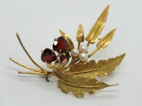 A large 9ct gold floral brooch set with garnet and pearls, stamped 9ct, approx 5.5cm tall, 9.3g.