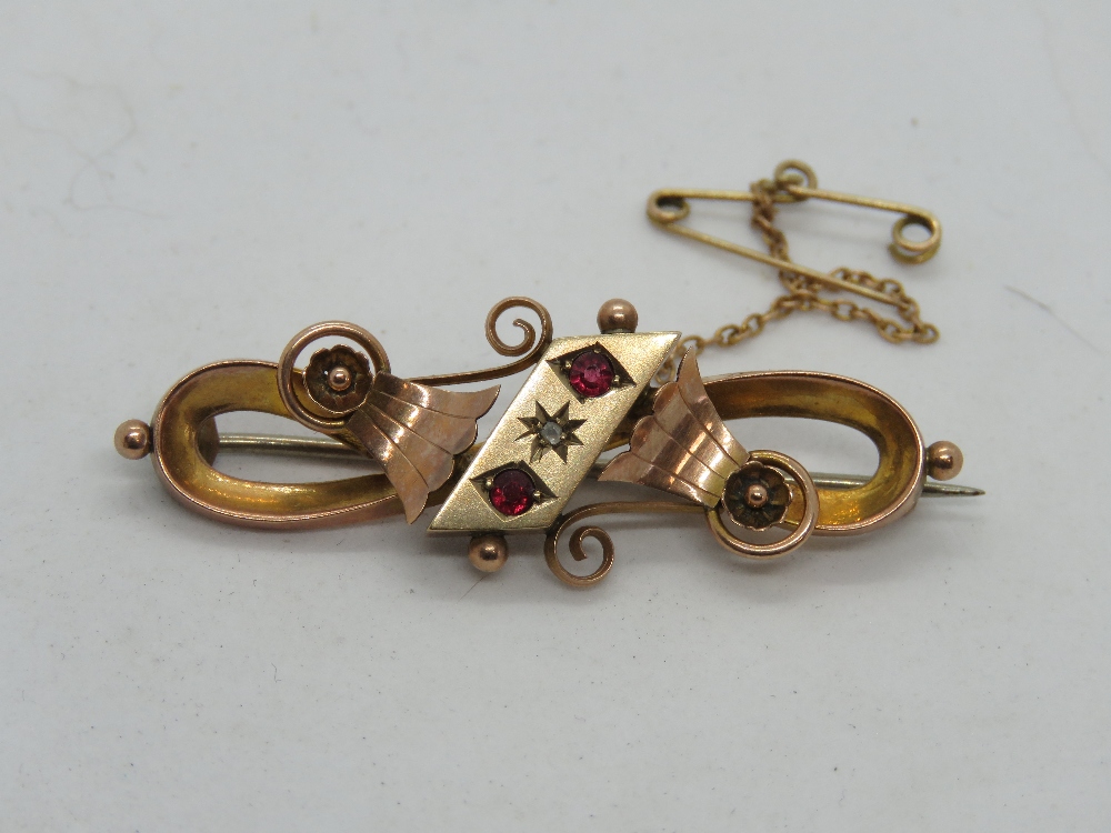 A 9ct rose gold brooch set with rubies and diamond, hallmarked for Chester, 3.5g.