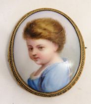 A portrait of a child on ceramic tile set within a brooch frame, approx 4.4 x 3.