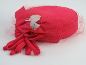 A pillbox type hat with net and floral decoration upon.