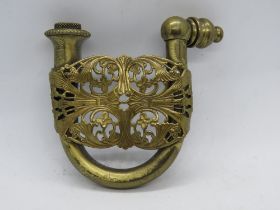 A c1970s brass hidden pipe belt buckle with pierced floral design.