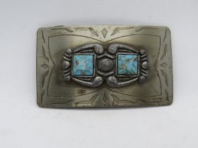 A Native American style belt buckle having two square cut turquoise cabachons upon.