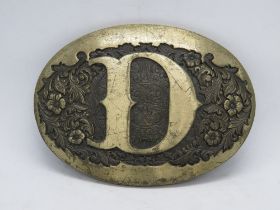 An Award Design Medals Inc belt buckle with D design upon.
