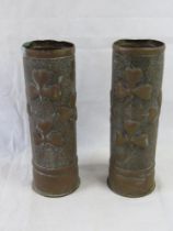 A pair of brass trench art shell casings, clover designs upon.