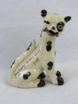 A Torquay motto ware winking cat approx 6" high, red clay with cream glaze and yellow glass eye.
