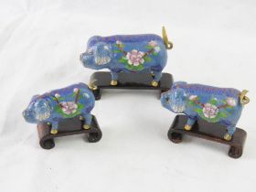 A set of three graduated Cloisonné pigs with stands.