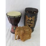 Two African drums together with a carved wooden elephant.