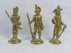 A set of three cast brass military figurines.