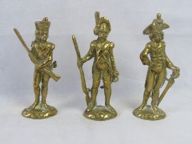 A set of three cast brass military figurines.