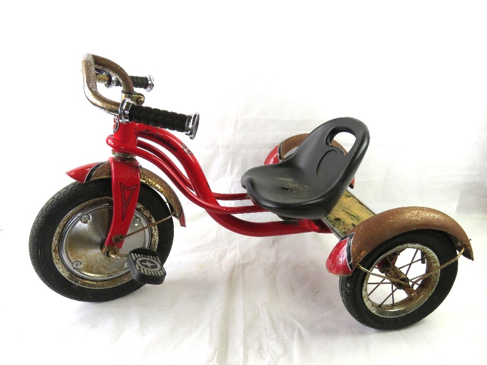 A Child's Schwinn tricycle, original pedals, some water damage to wooden panel to rear.