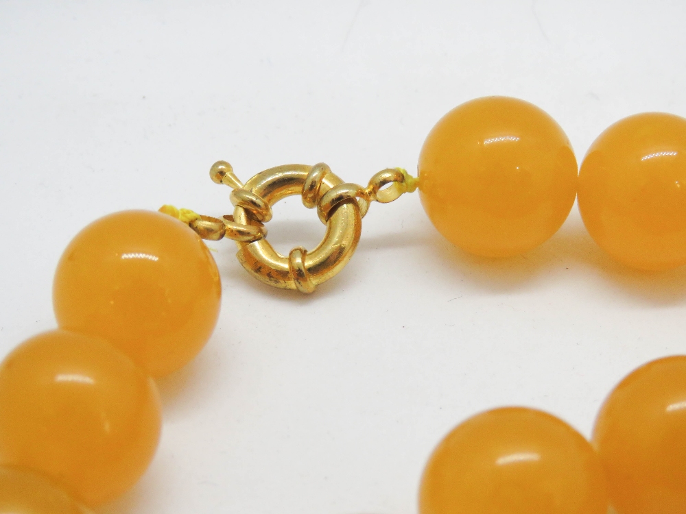 A yellow Jade bead necklace strung with thread 74cm, each bead approx 20mm dia, having gilded clasp, - Image 3 of 3