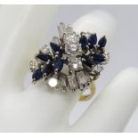 A modern sapphire and diamond cluster ring comprised of three central brilliant cut diamonds in a
