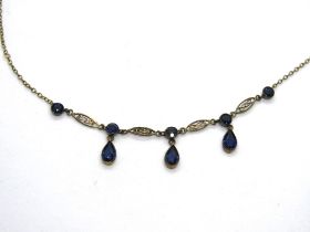 An early 20th century necklace set with blue paste stones and having filigree panels,