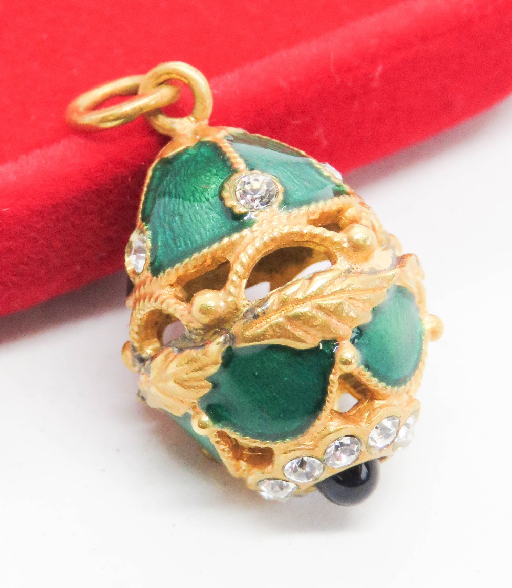 A 'Faberge' type egg charm having green enamel, white and blue stone decoration upon.