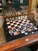 A BRONZE CHESS SET ON A INLAID BLACK LIMESTONE BOARD, THE KINGS. H 14.5cms.