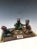A COLD PAINTED BRONZE GROUP OF THREE NORTH AFRICAN BOYS PLAYING DICE ON A CARPET WITH GILT TASSEL