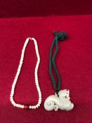 A CHINESE NEPHRITE JADE PENDANT PIERCED AND CARVED AS A QILIN. W 6.5cms. TOGETHER WITH A STRING OF