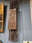 A MID CENTURY AMERICAN BURWOOD PRODUCTS WOODEN WALL TIMEPIECE WITH A RECTANGULAR DIAL BACKED BY