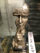 A WHITE METAL CAST BUST OF A MAN SIGNALLING SILENCE WITH A FINGER TO HIS LIPS