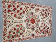 AN UZBEK SUSANI EMBROIDERED IN RED, YELLOW, GREEN AND BLUE WITH A CENTRAL EIGHT PETAL FLOWER